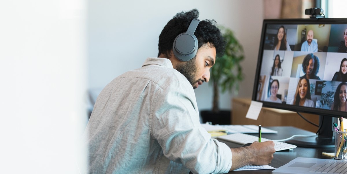 man working at a desk, attending virtual meeting